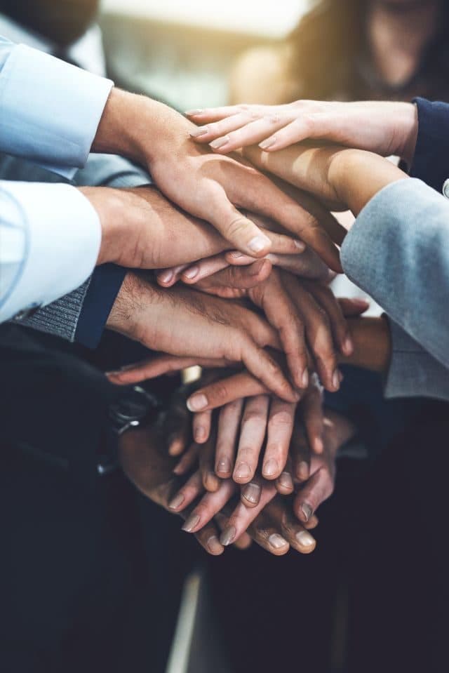 Team members joining hands in partnership